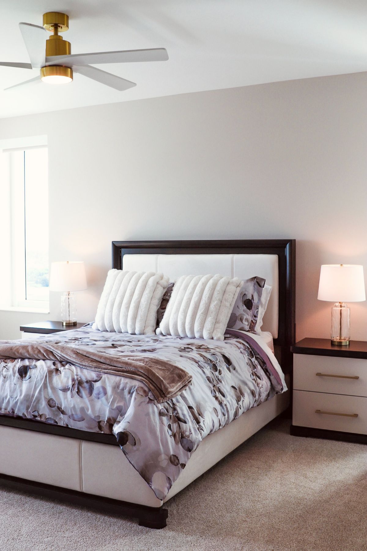 Bedroom with bed, nightstands, ceiling fan, and window. Neutral colors; floral bedding.