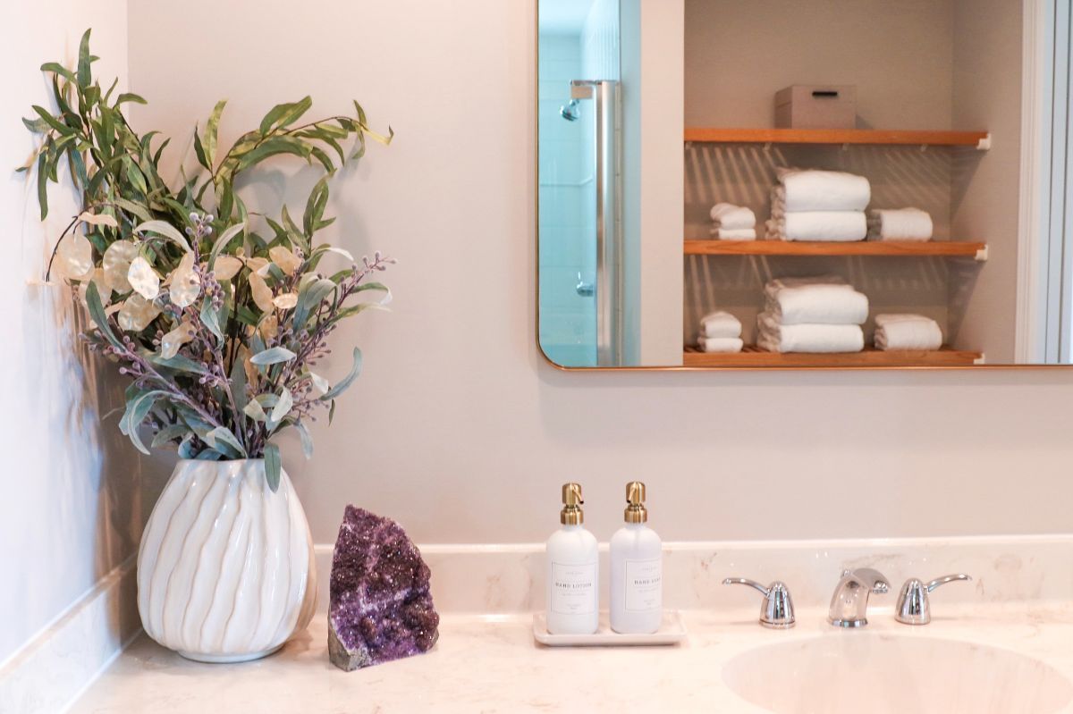 Bathroom vanity with white marble, vase with flowers, and mirrored medicine cabinet with towels.