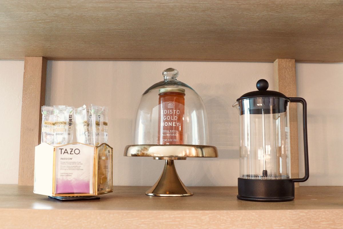 Shelf with Tazo tea, a glass-domed cake stand, and a French press.