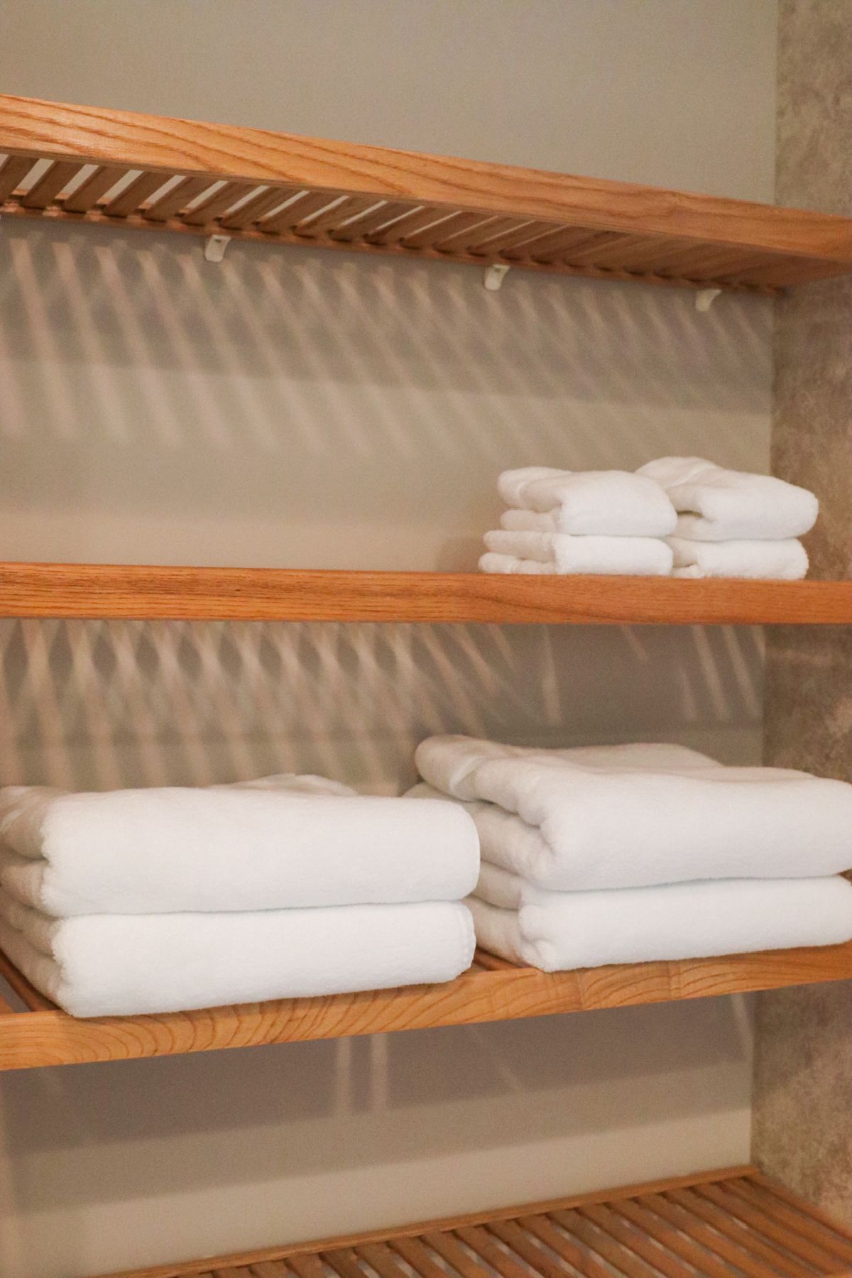 Wooden shelves holding folded white towels.