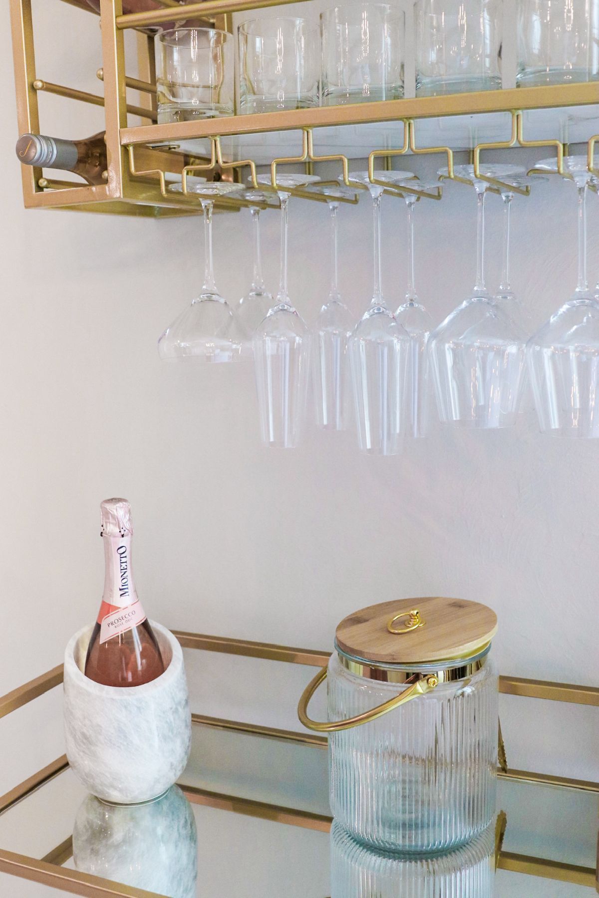 Gold bar cart with glasses, wine, ice bucket, and a bottle of pink champagne.