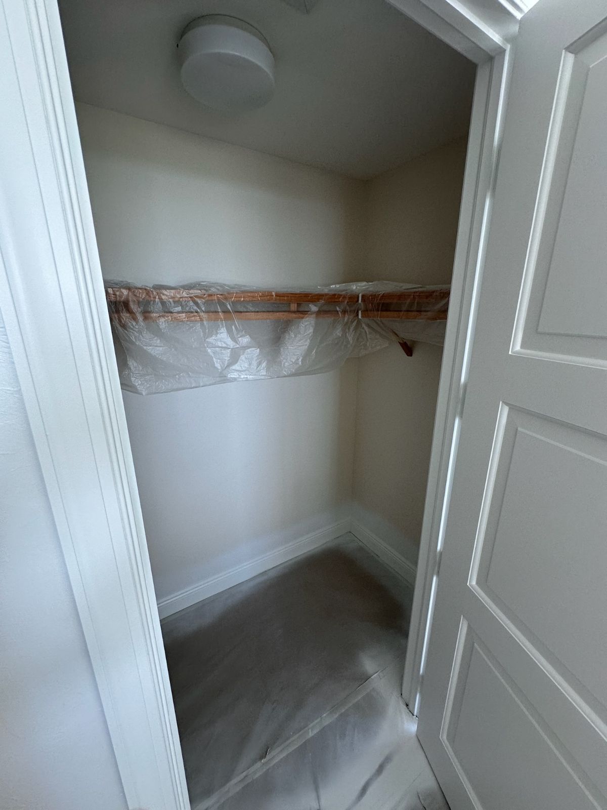 Small, empty closet with a shelf, white walls, and a light fixture.