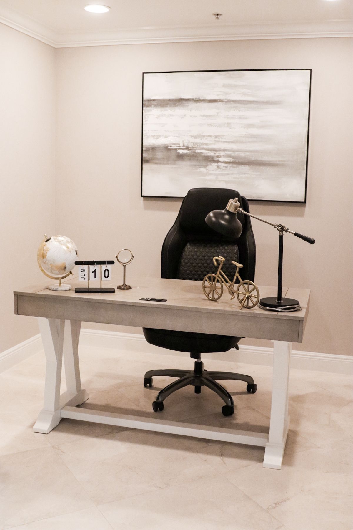 Office with desk, chair, artwork, globe, and calendar. Light-colored walls and flooring.