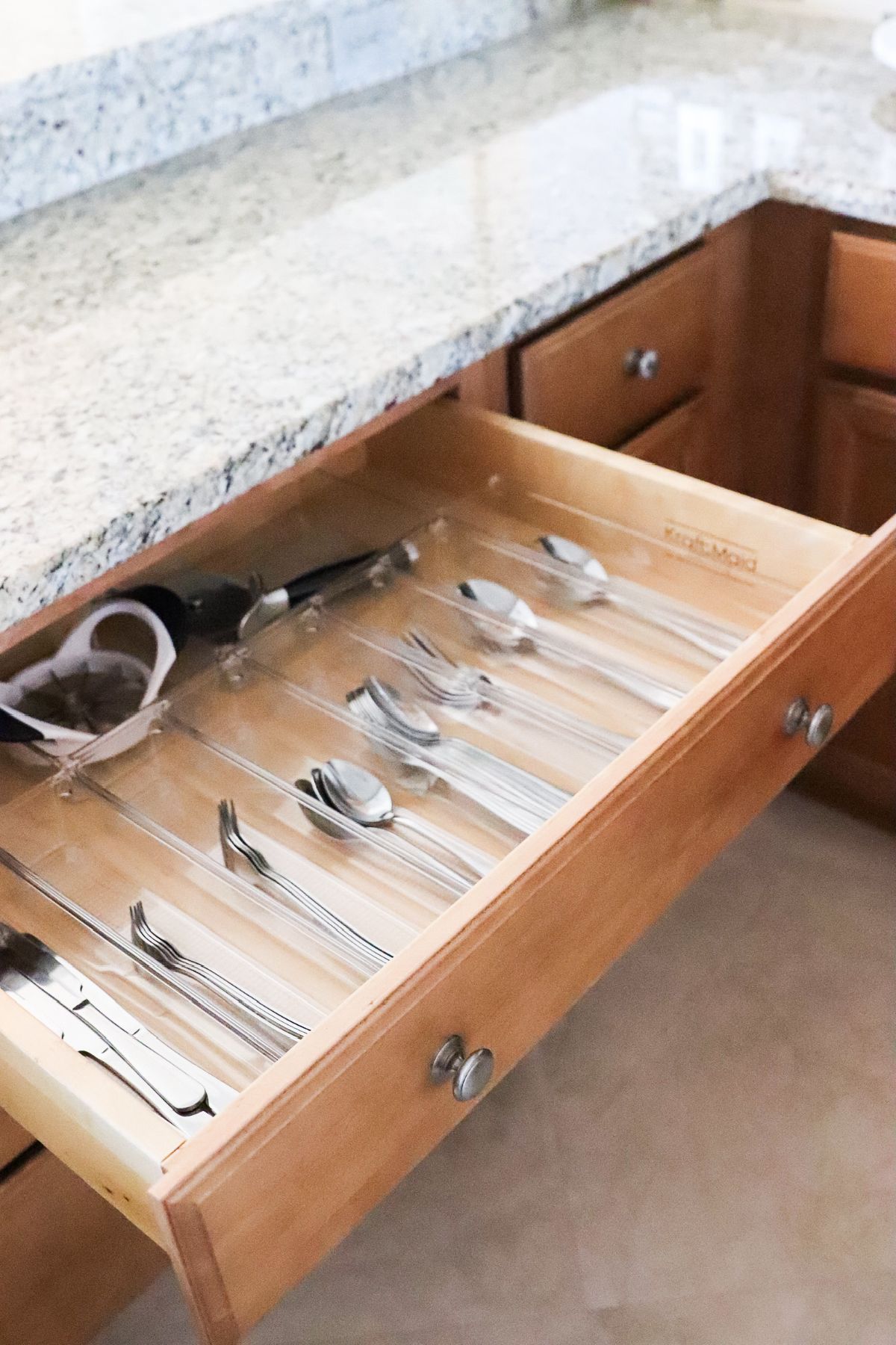Wooden kitchen drawer open with silverware neatly organized.