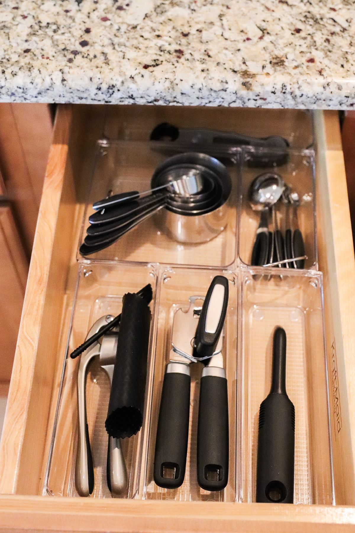 Kitchen drawer with organizers holding measuring cups, scoops, and utensils.