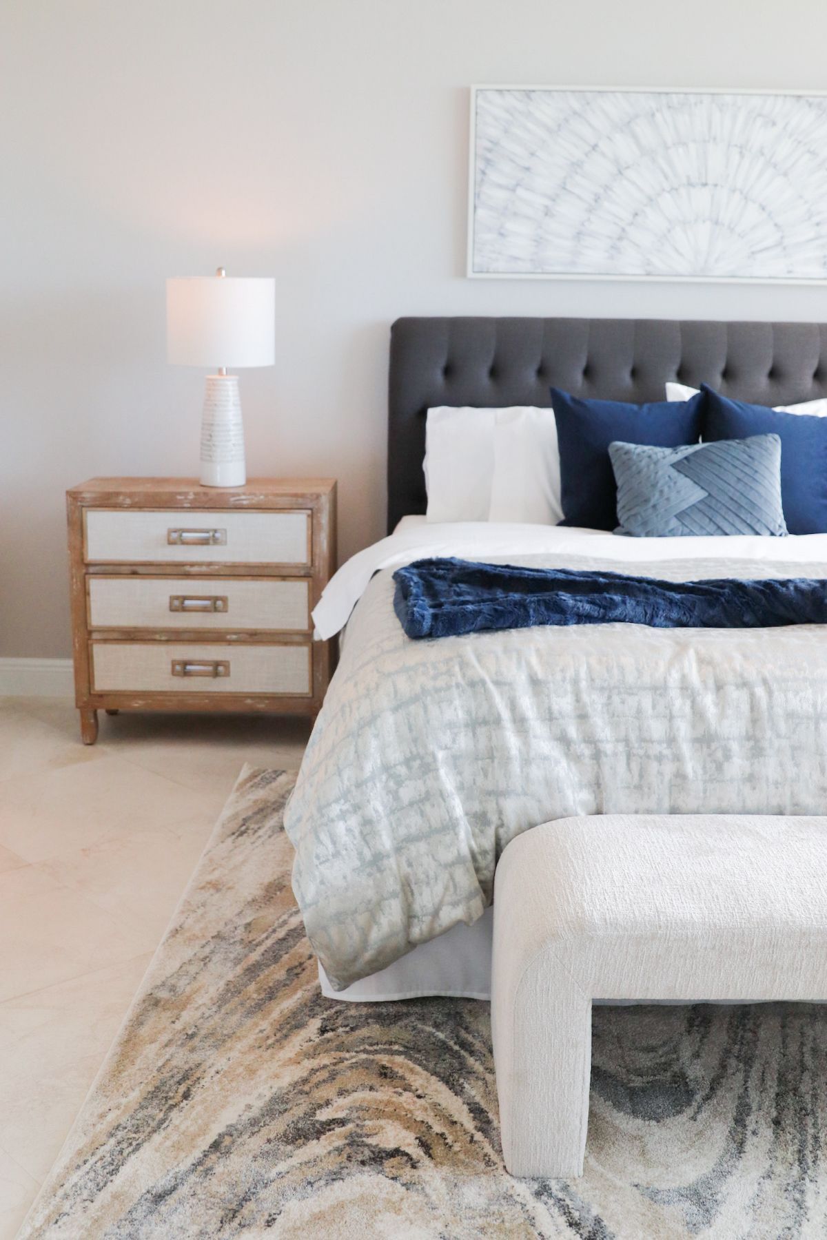 Bedroom with upholstered headboard, nightstand, and rug; blue and white color scheme.