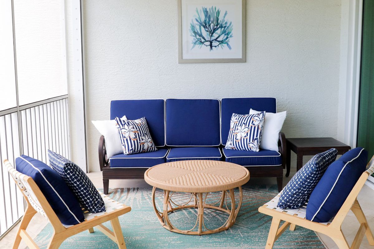 Outdoor patio with navy blue seating, a round coffee table, and a turquoise rug.