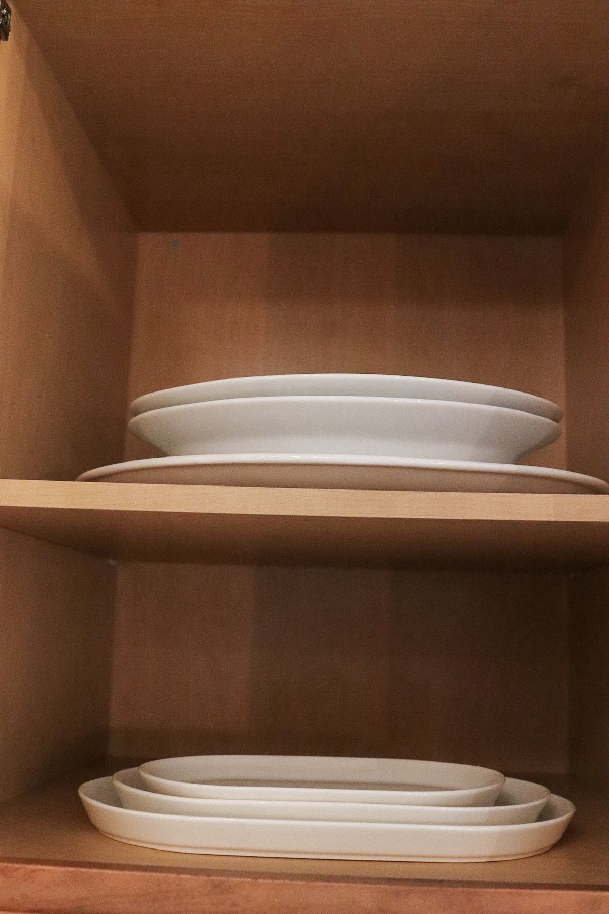 White plates stacked in a wooden cabinet.