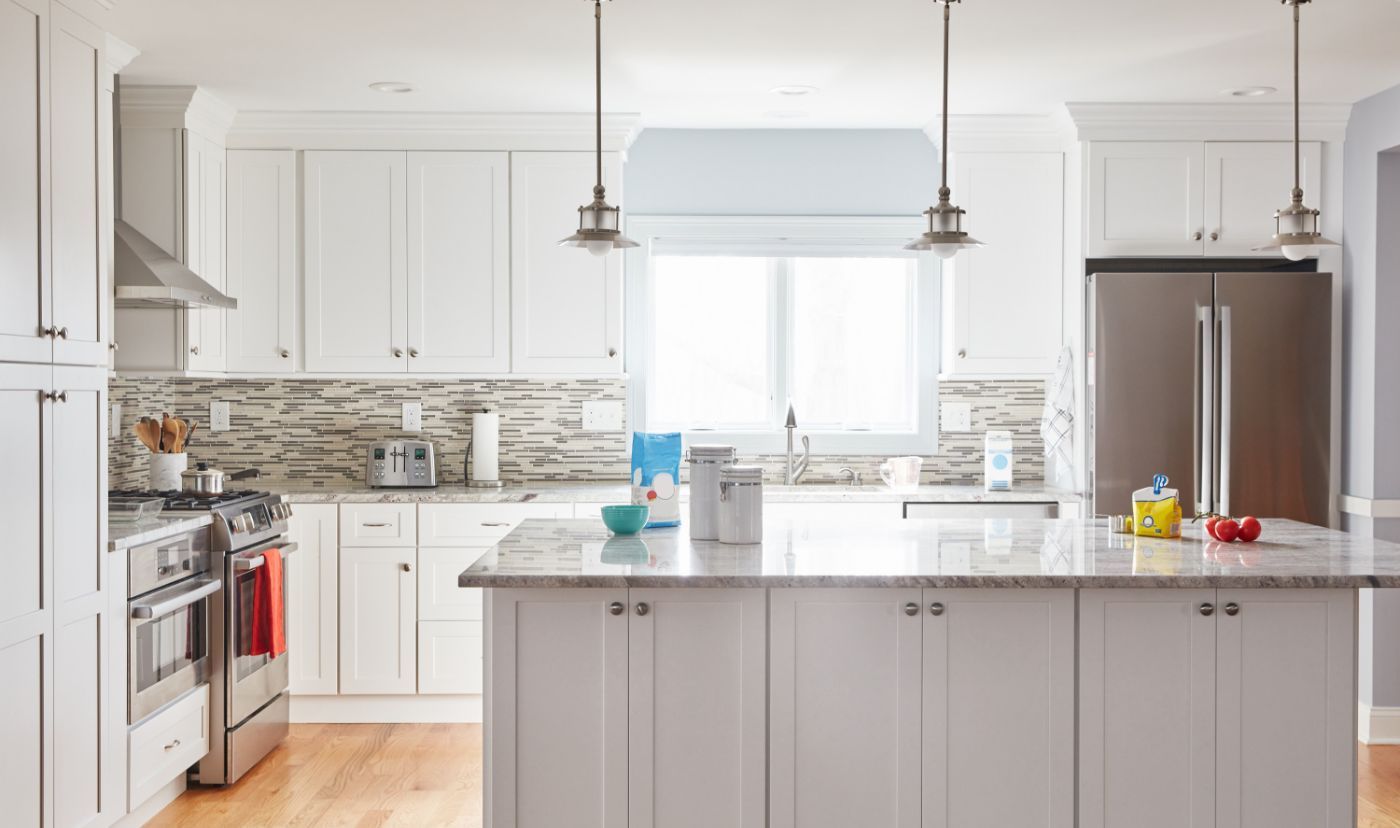White kitchen with island, stainless steel appliances, and wood flooring.