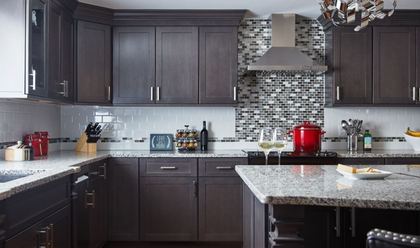 Dark wood kitchen with granite countertops, stainless steel appliances, and a tiled backsplash.