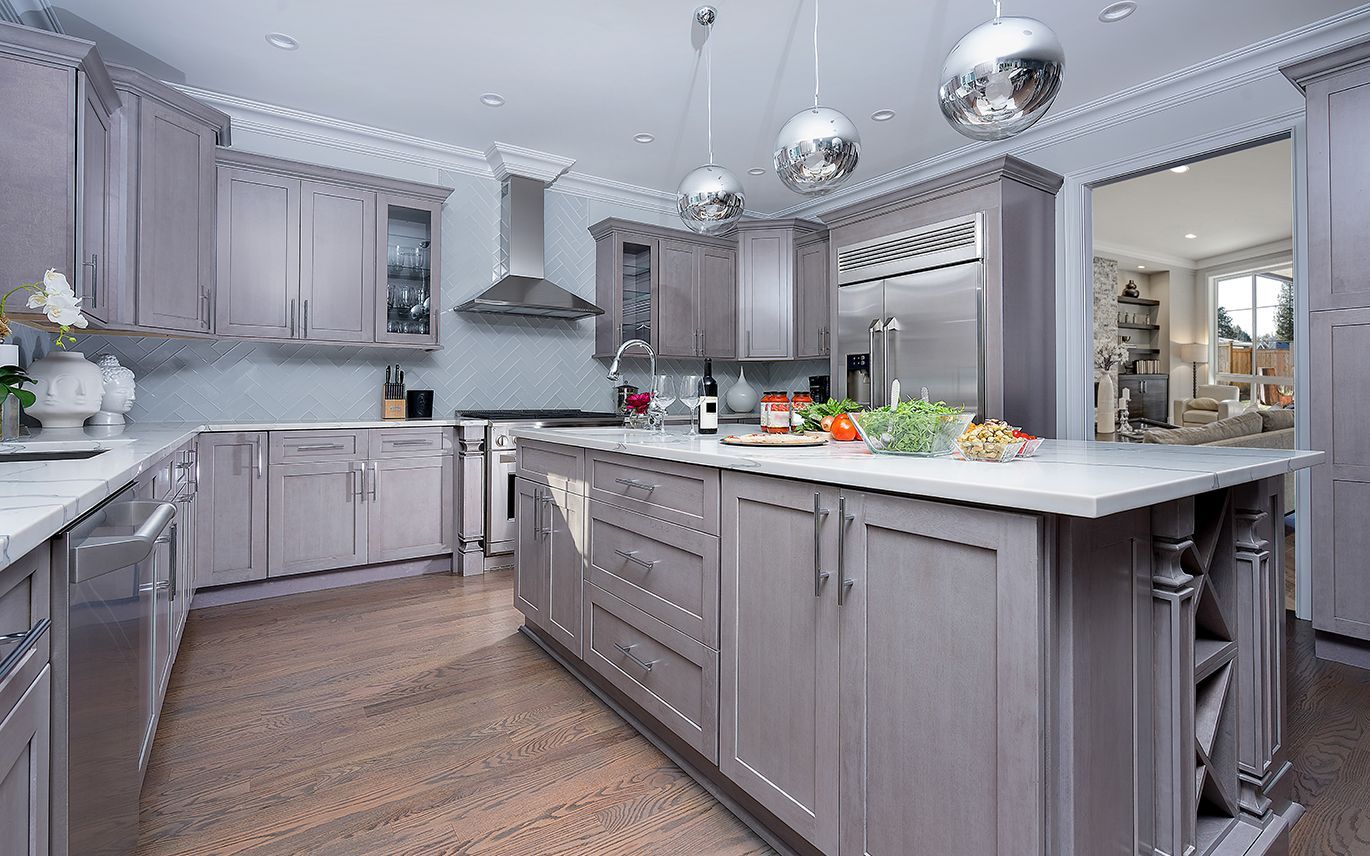 Gray kitchen with island, stainless steel appliances, and wood flooring.