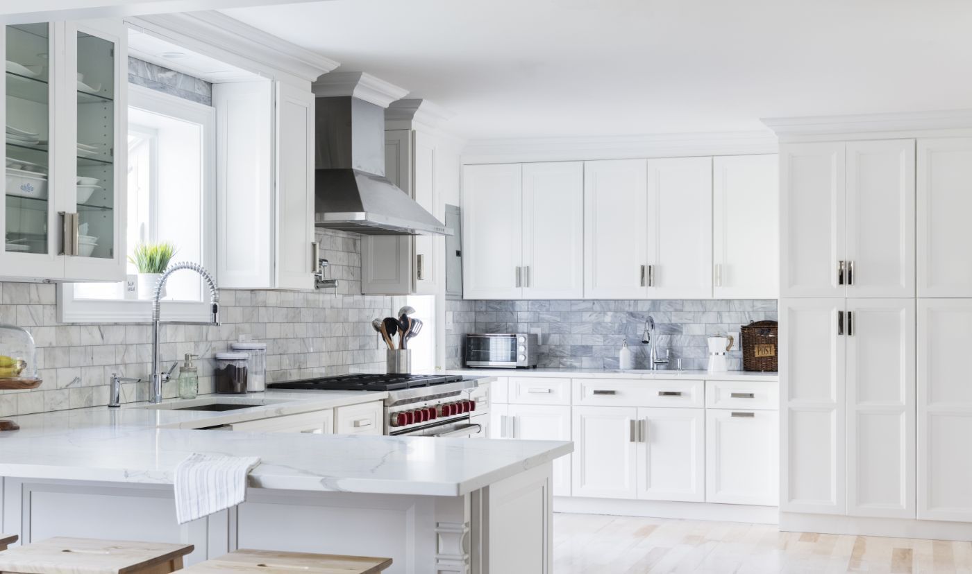 Bright white kitchen with stainless steel appliances, white cabinets, and marble countertops.