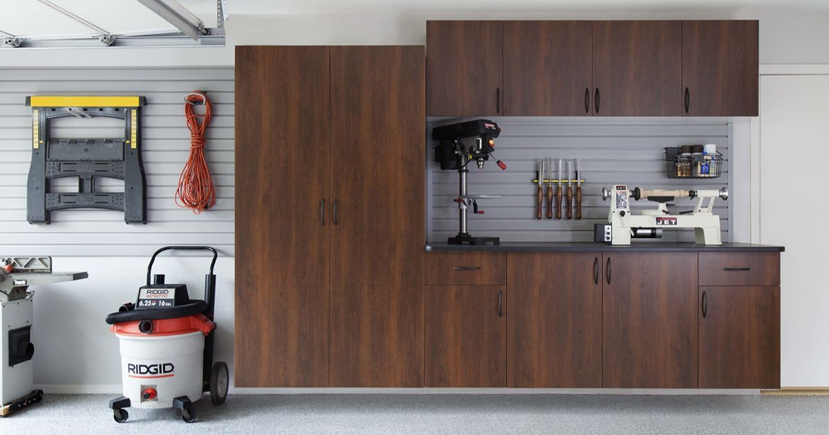 Garage workshop with brown cabinets, tools, and a vacuum cleaner.
