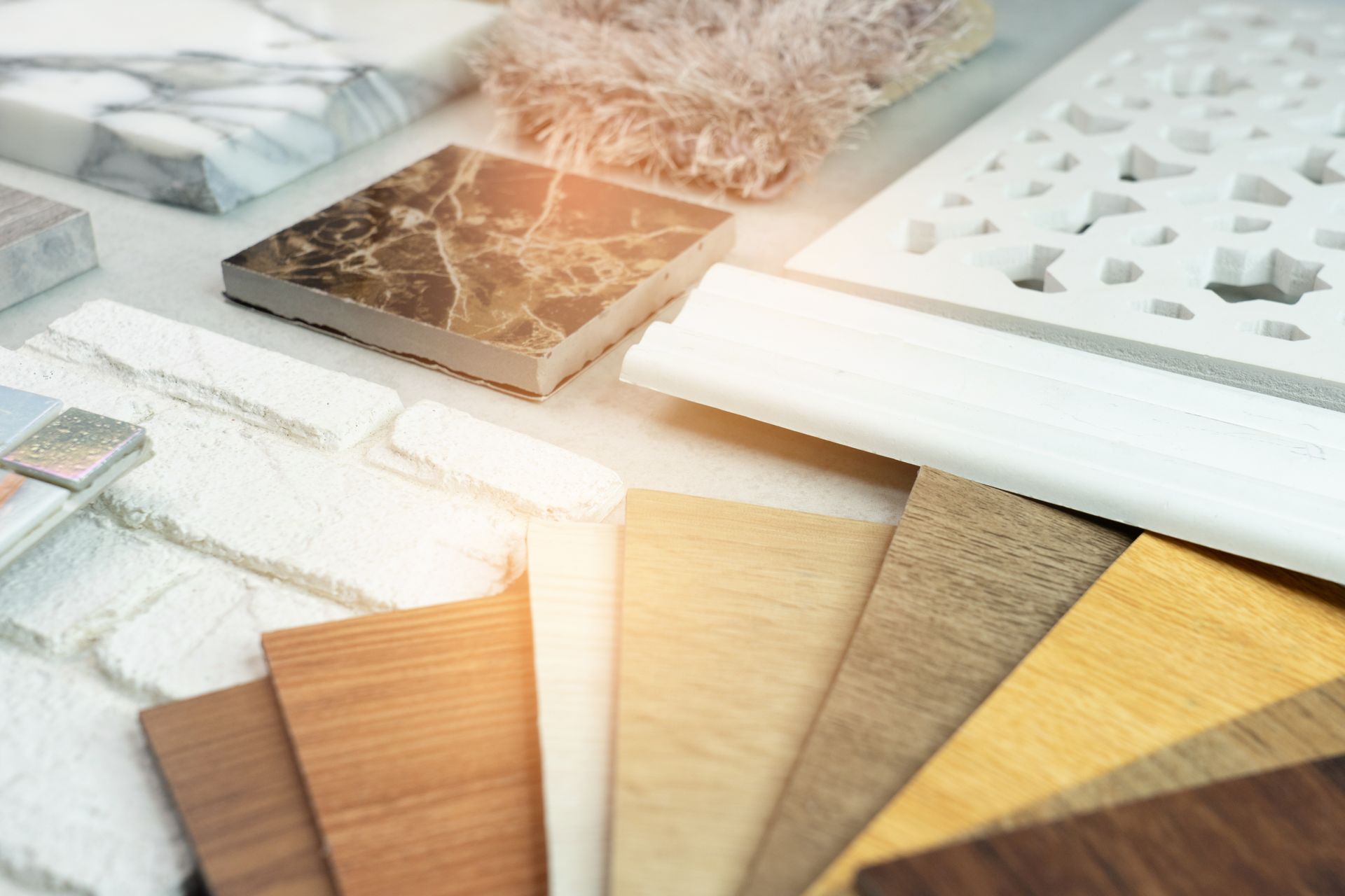 A flat lay of various interior design material samples, including wood veneers, white brick, marble tiles, and fabric.