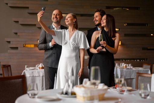 Four people taking a selfie in a restaurant. Two hold champagne glasses.