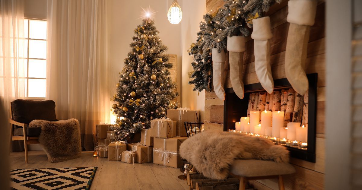 Cozy Christmas room: tree, fireplace with stockings, lit candles, wrapped gifts, sheepskin throws, and a window.