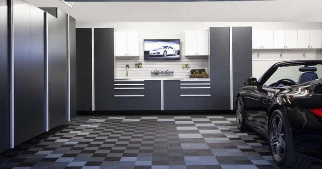 A sleek, organized garage with a black sports car. The floor is checkered, and cabinets are gray and white.