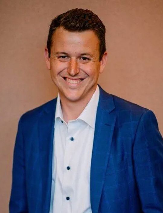 A man in a blue suit and white shirt is smiling for the camera.