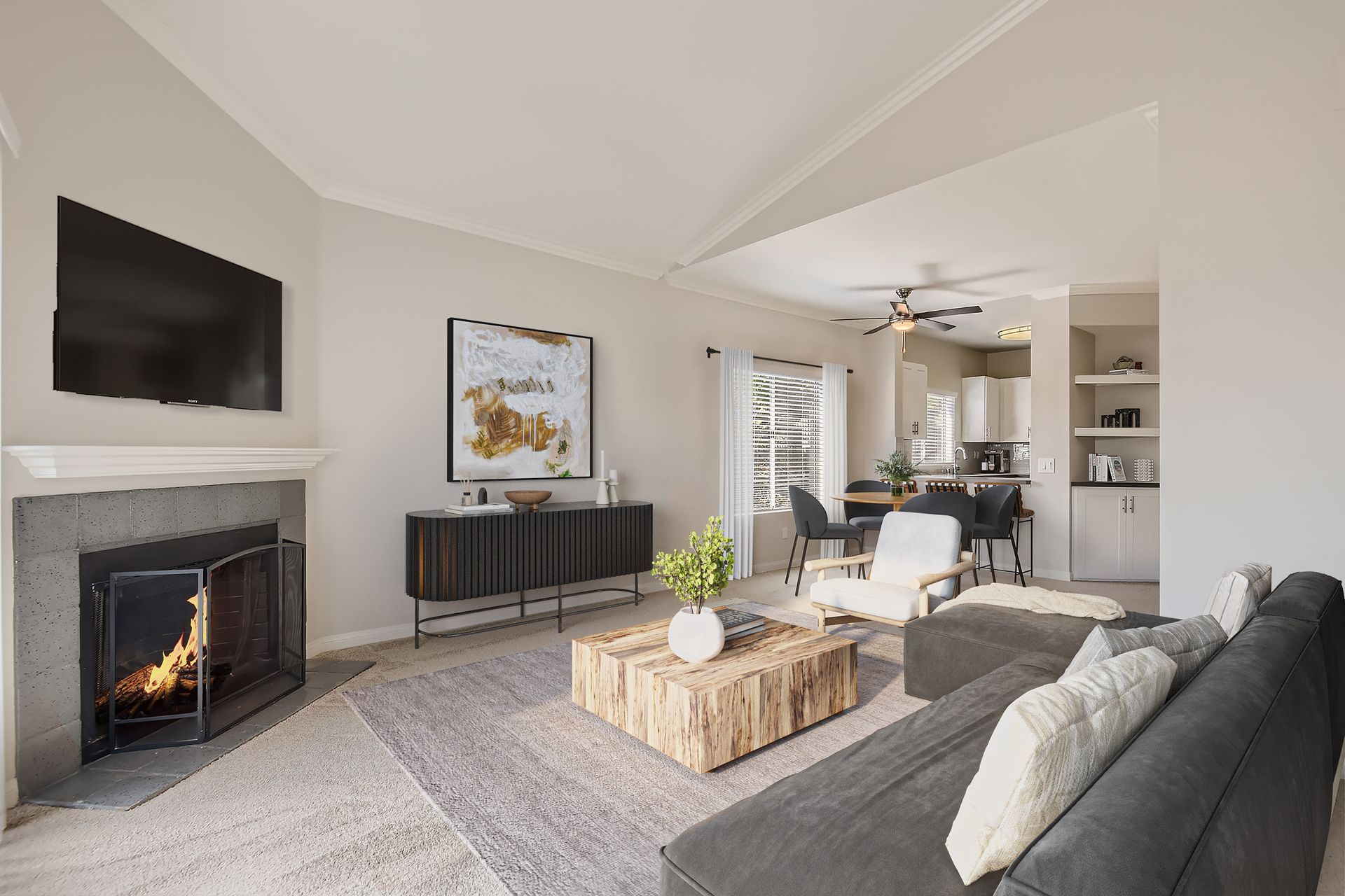 Living room in a modern apartment with a fireplace, wall-mounted TV, and open kitchen.