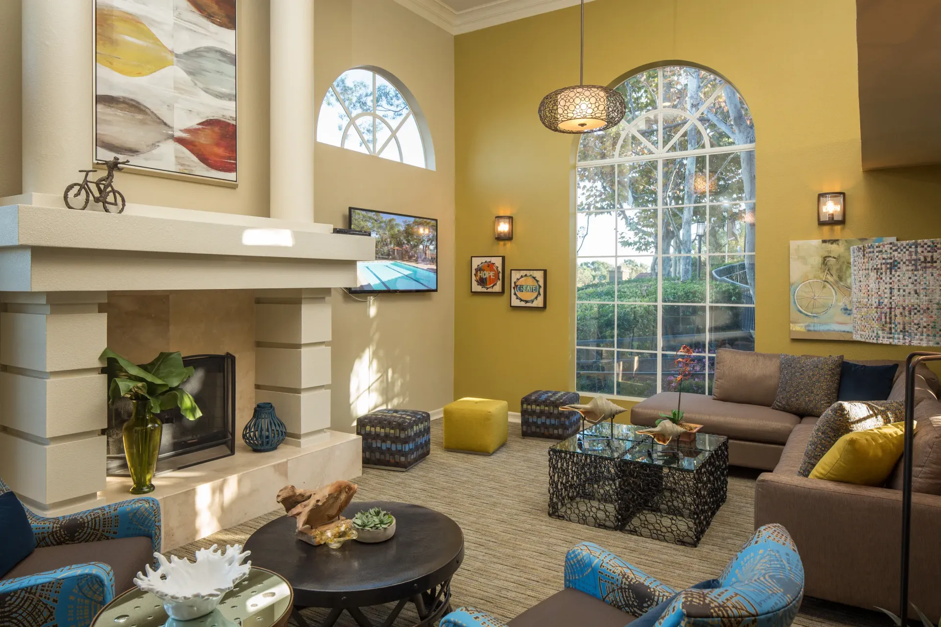 Interior community lounge with fireplace, large arched windows, and comfortable seating.