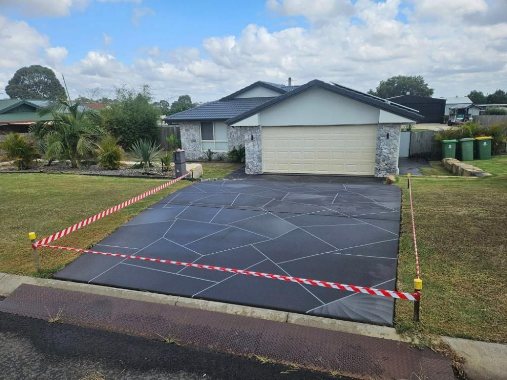 A Driveway Is Being Painted in Front of A House — SRS Concreting in Toowoomba, QLD