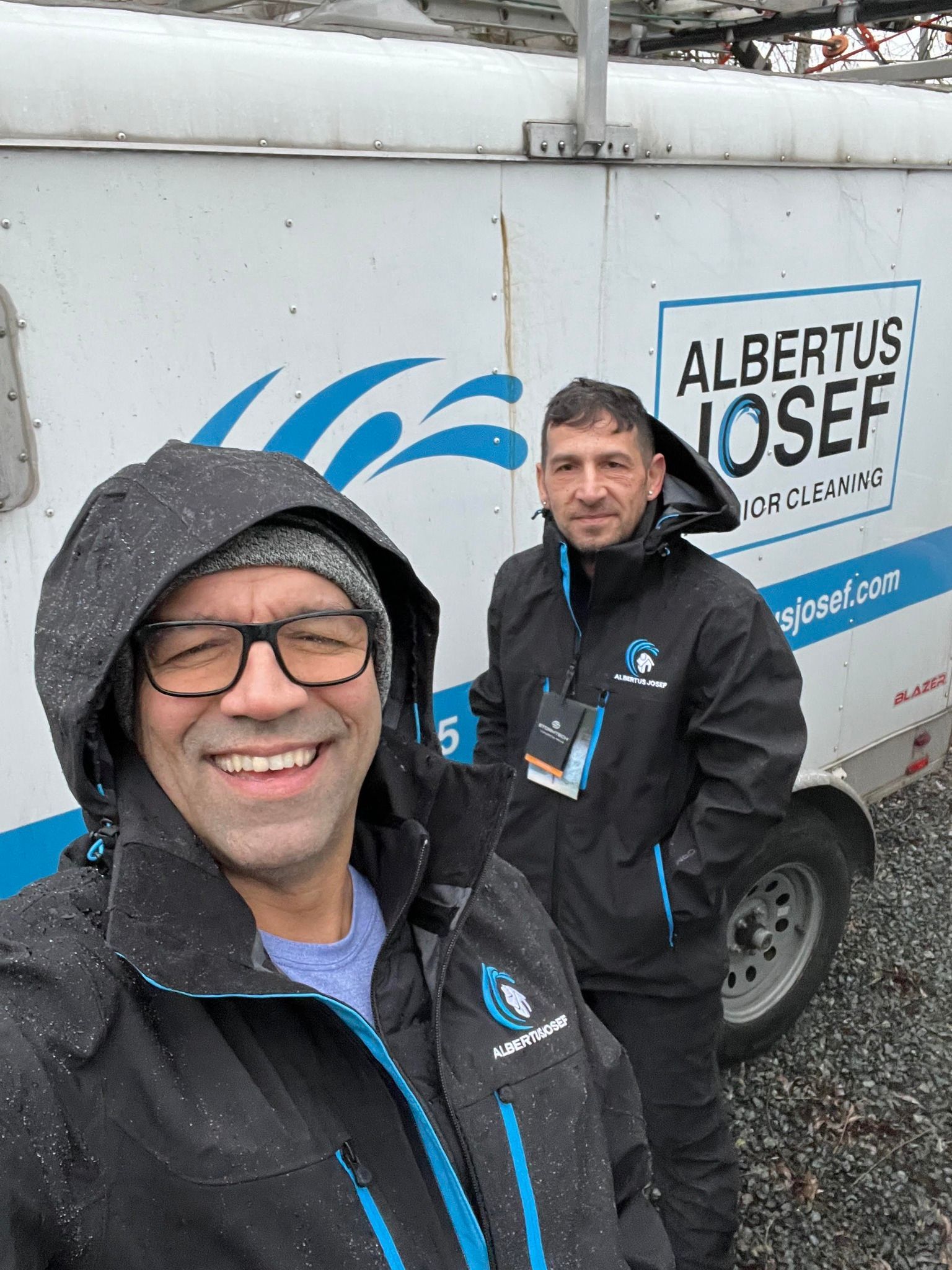 Two men are standing in front of a albertus josef truck