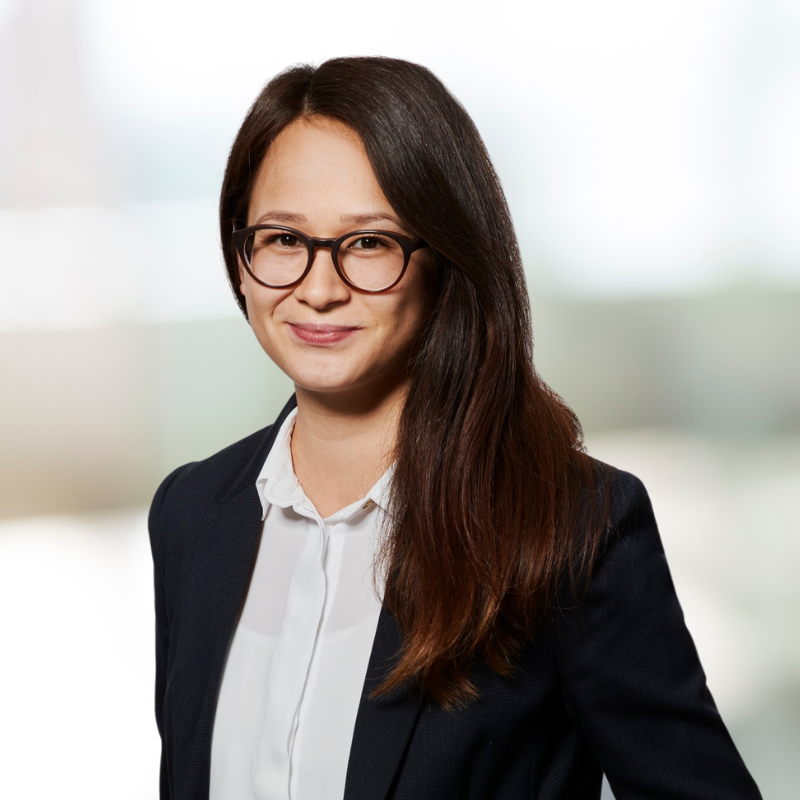 Eine Frau mit Brille und Jacke lächelt in die Kamera