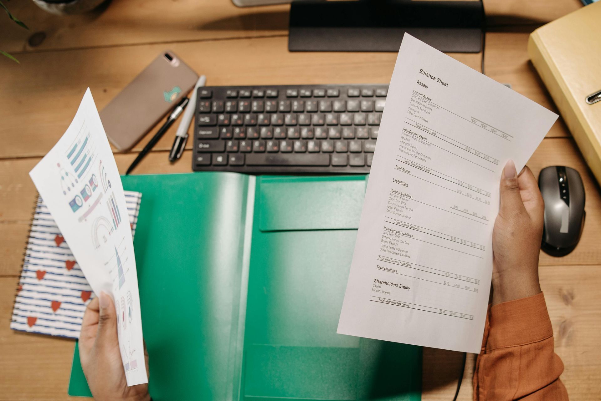 Eine Person hält ein Blatt Papier vor einem Computer.