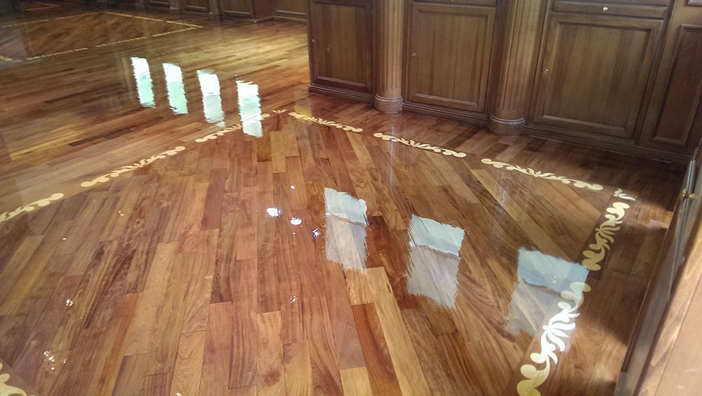 A wooden floor in a kitchen with a reflection of the floor in the mirror.