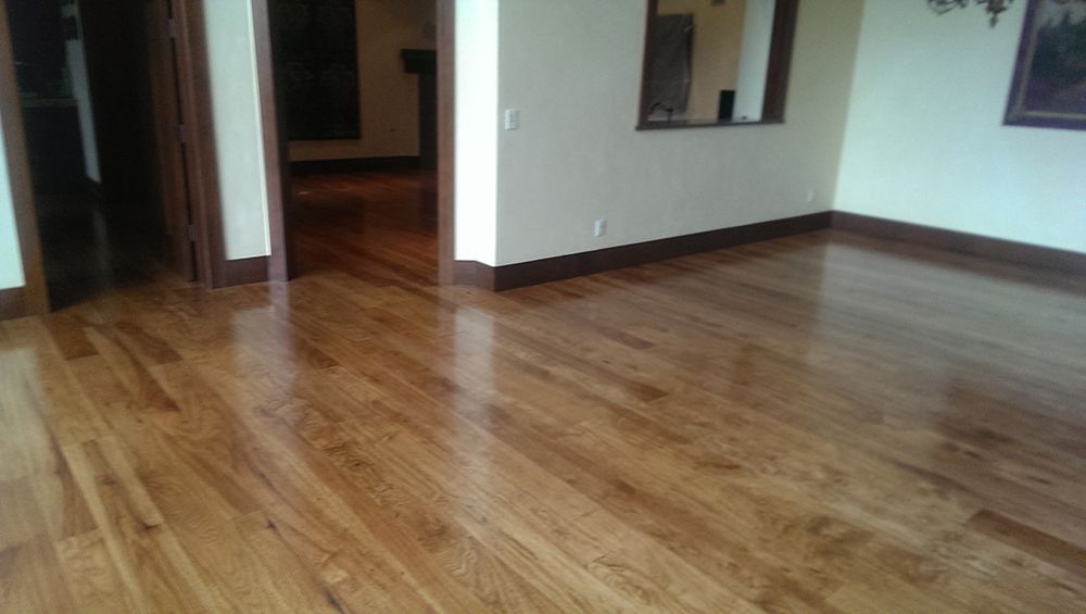 A living room with hardwood floors and a dining room in the background.