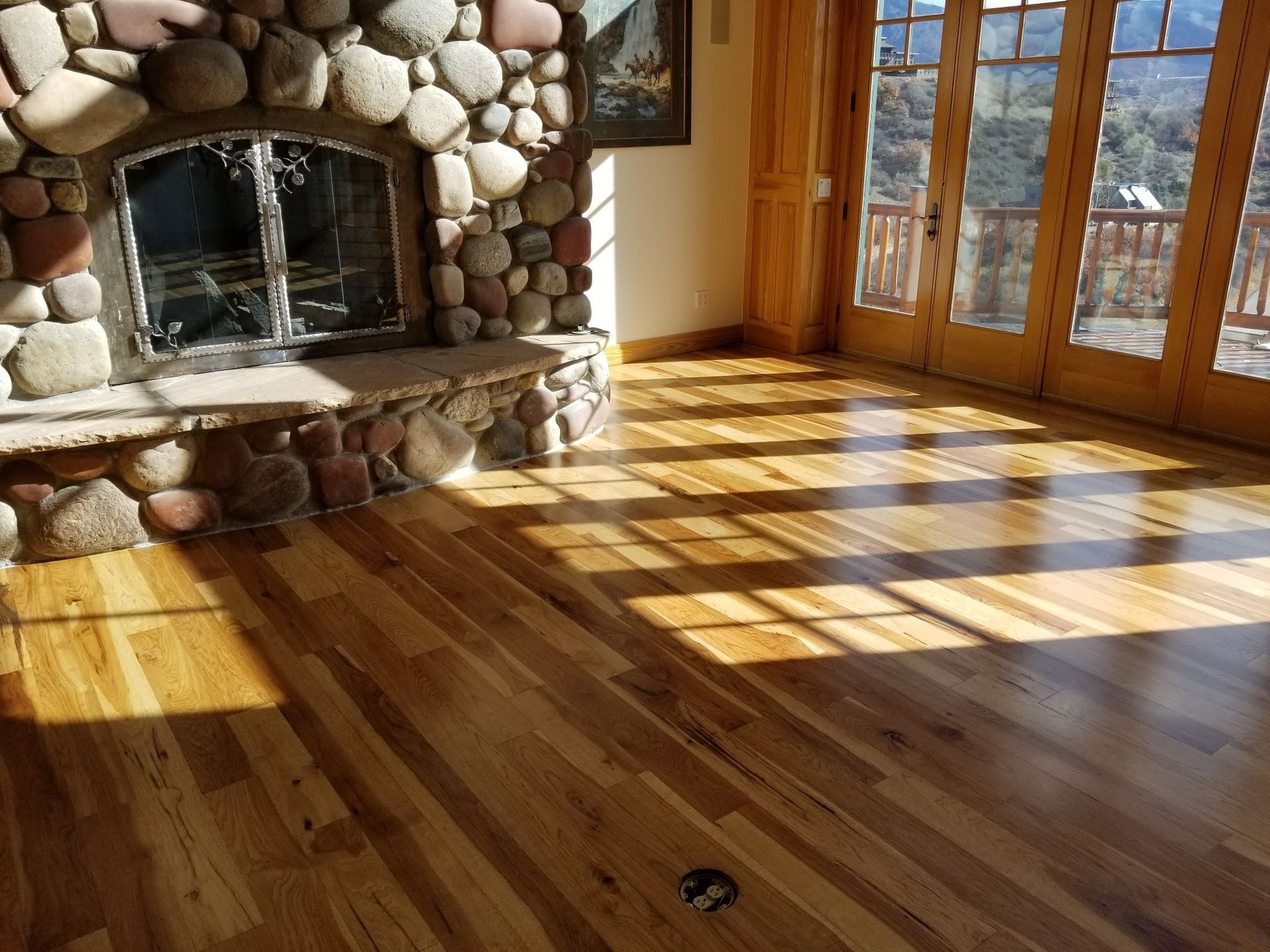 A living room with hardwood floors and a stone fireplace