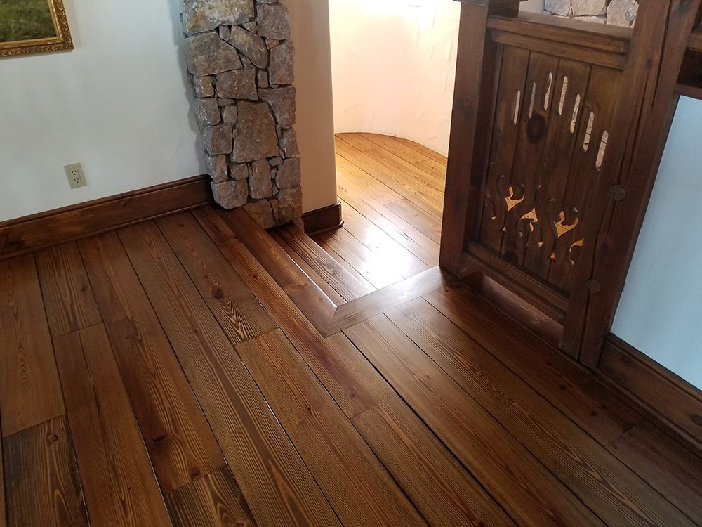 A room with hardwood floors and a stone fireplace.