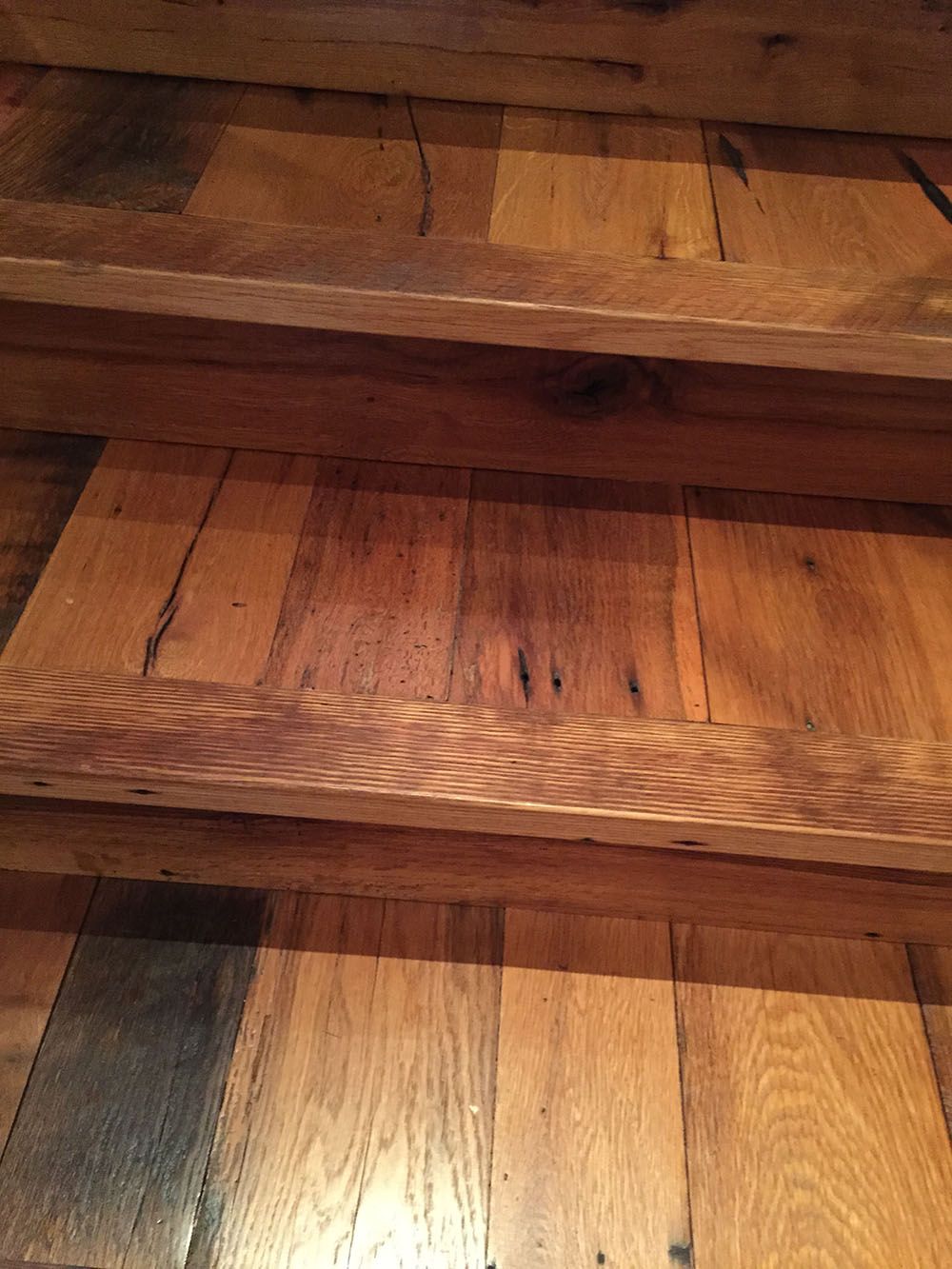 A close up of a wooden staircase with a wooden railing.