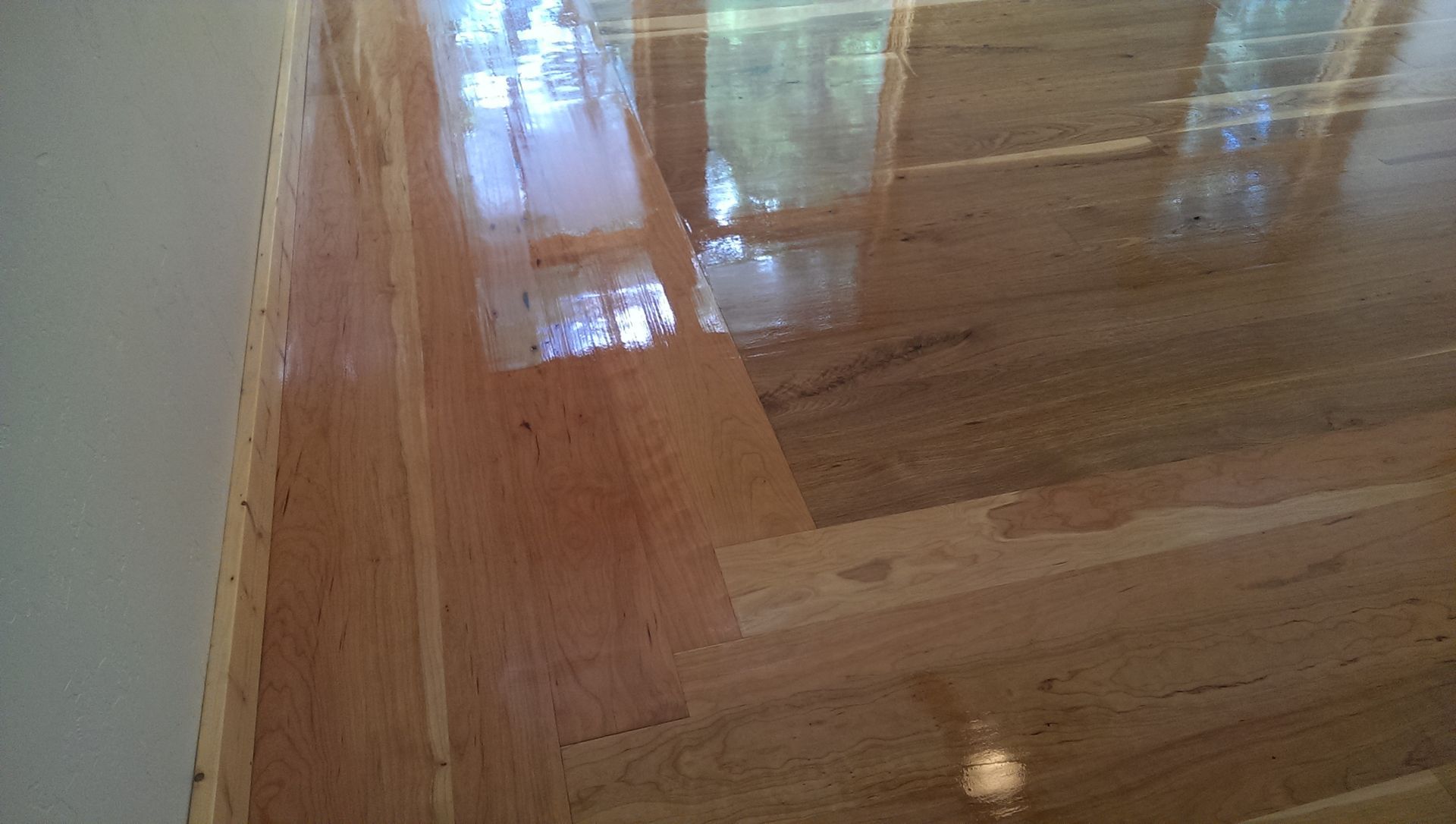 A close up of a shiny wooden floor in a room.