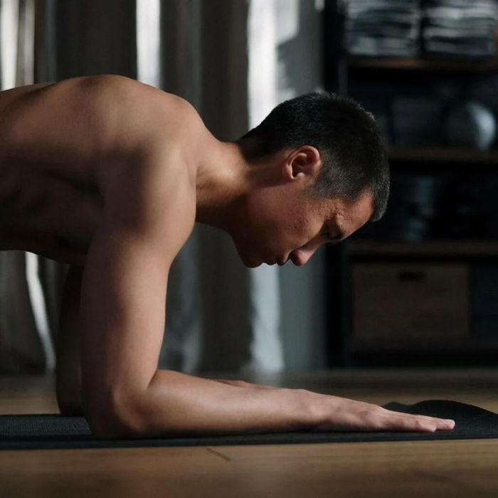 A shirtless man is doing a plank on a yoga mat.