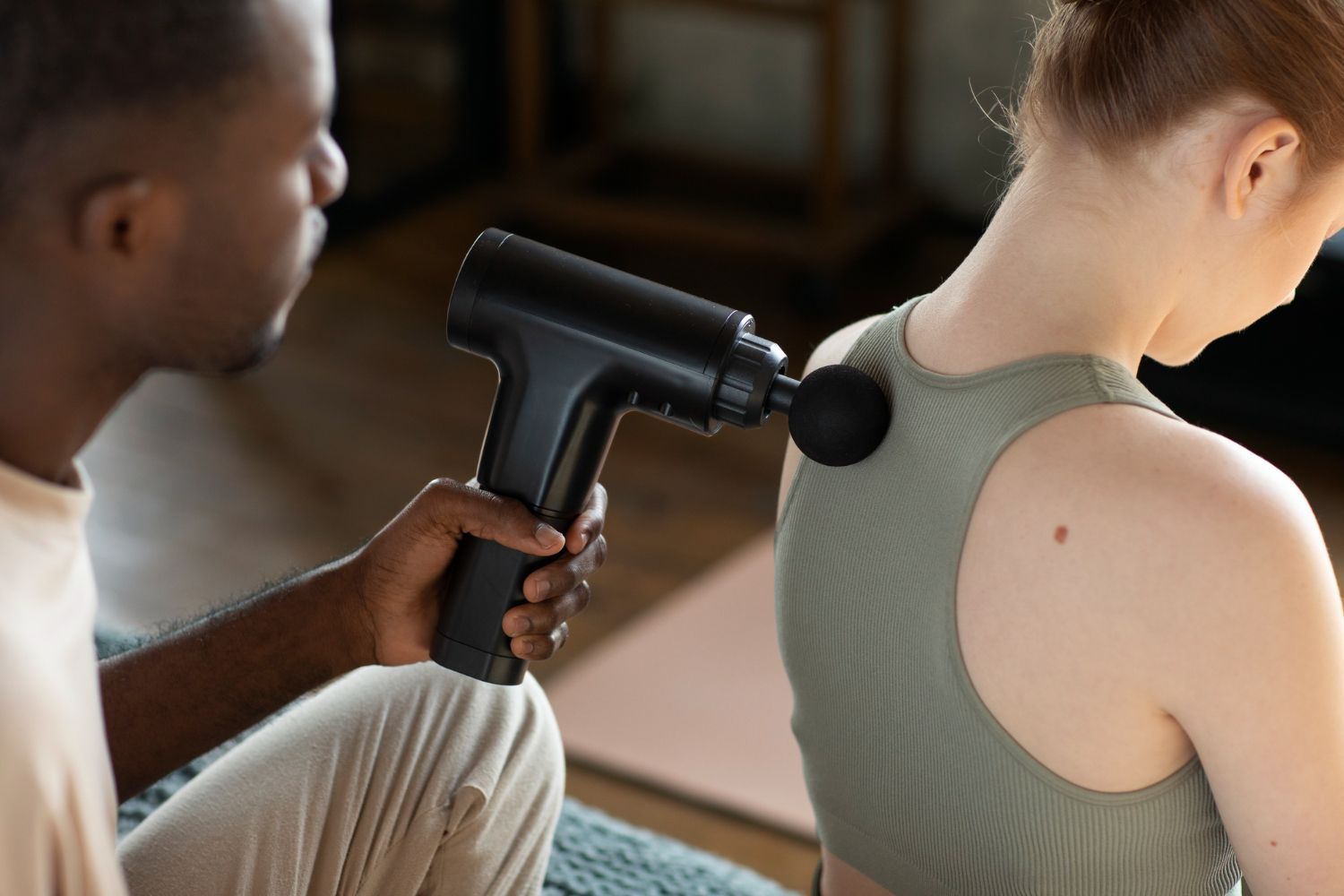 Man using massage gun on woman.