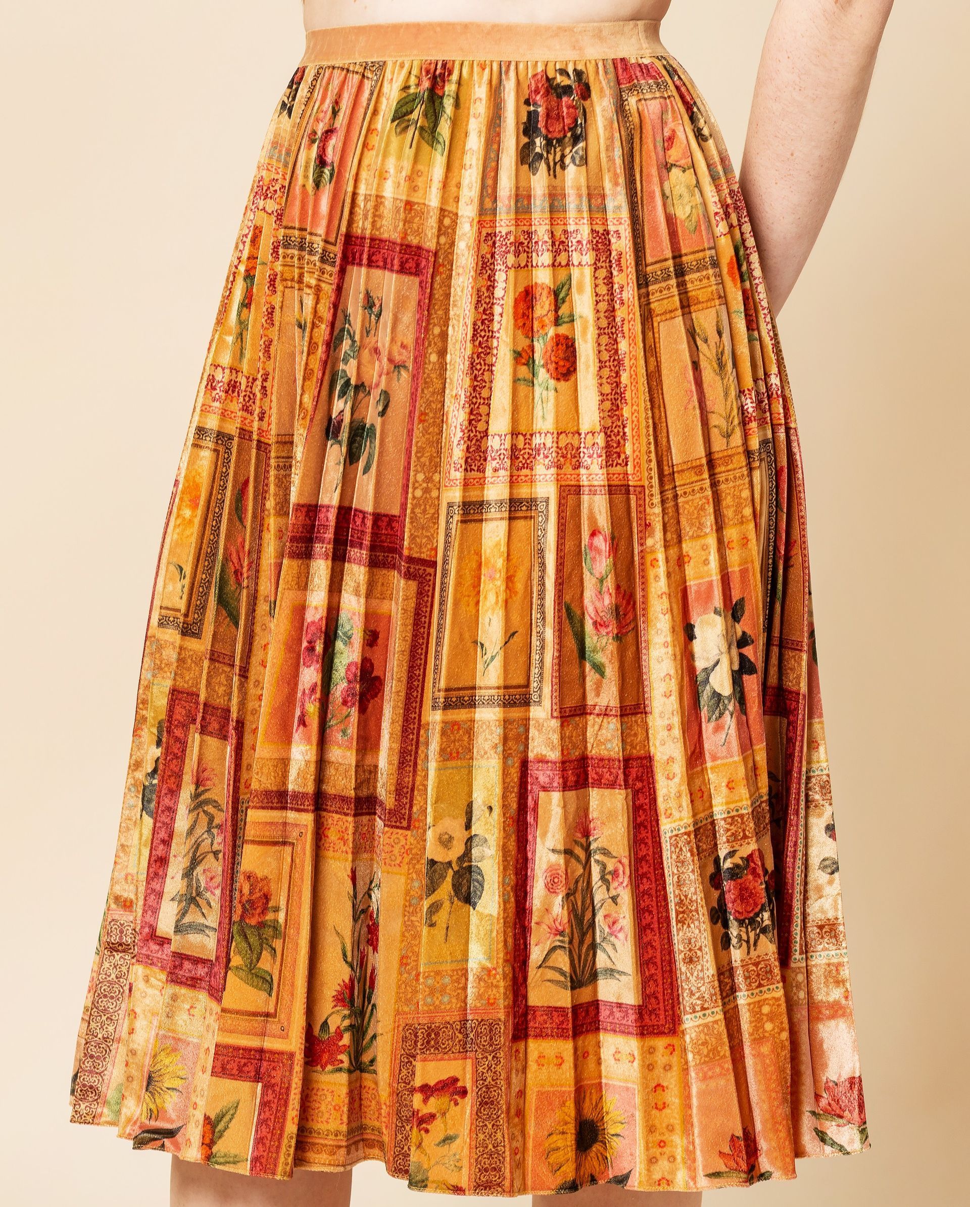 Gonna plissettata di media lunghezza con stampa floreale in stile vintage arancione e oro e motivi rettangolari incorniciati.