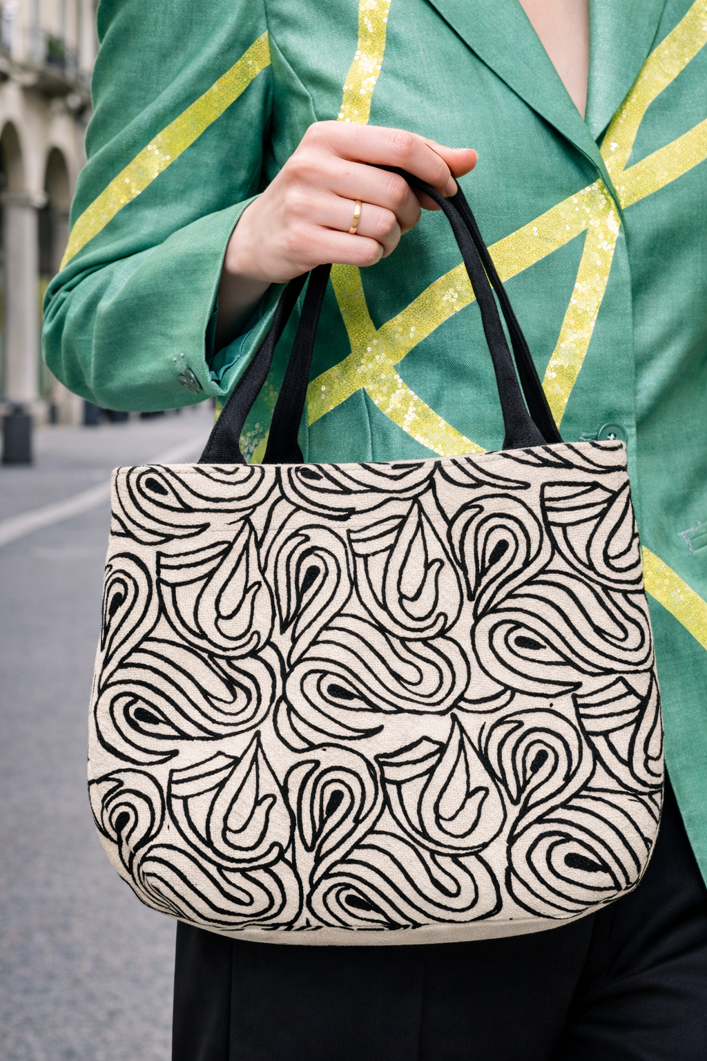 Primo piano di un colletto in velluto verde con perline e decorazioni elaborate su una giacca verde con fantasia.