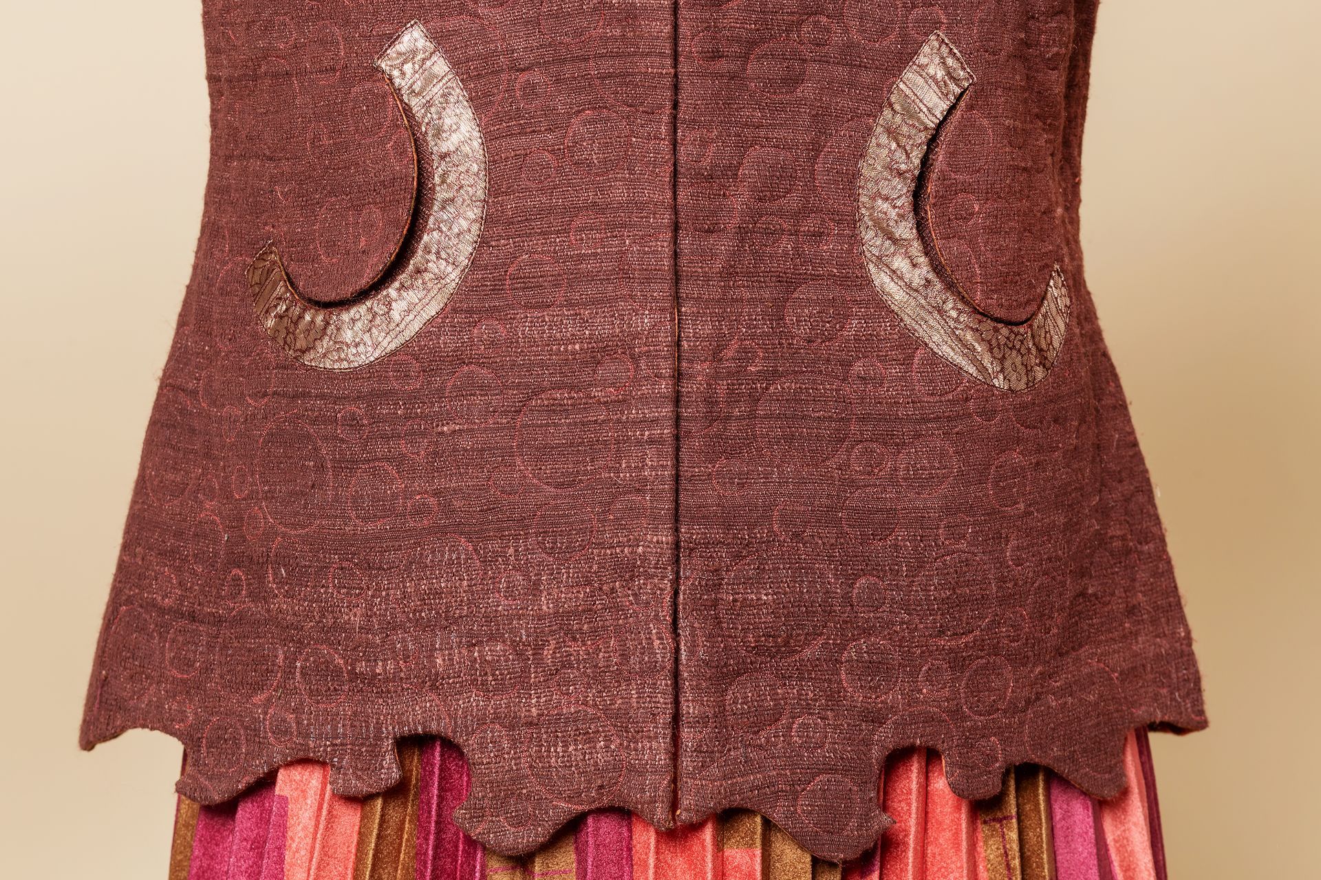 Gilet in tessuto bordeaux con orlo smerlato e dettagli a mezzaluna dorati.