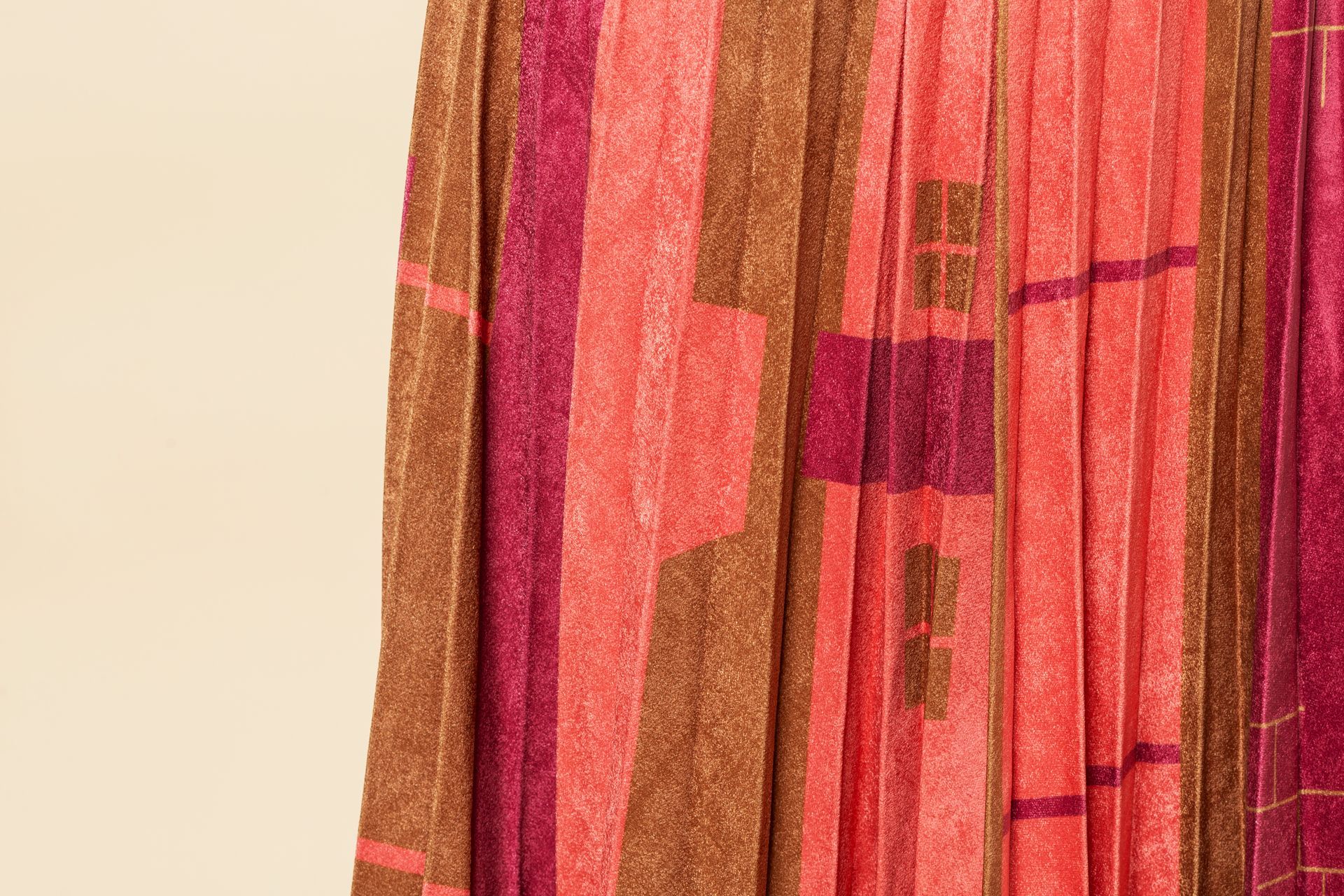 Tessuto plissettato con strisce verticali nei toni del marrone, rosa e rosso.