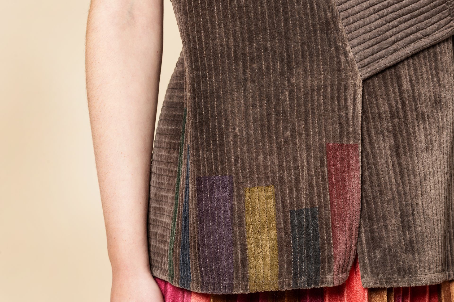 Donna con top marrone a coste con rettangoli colorati vicino all'orlo.