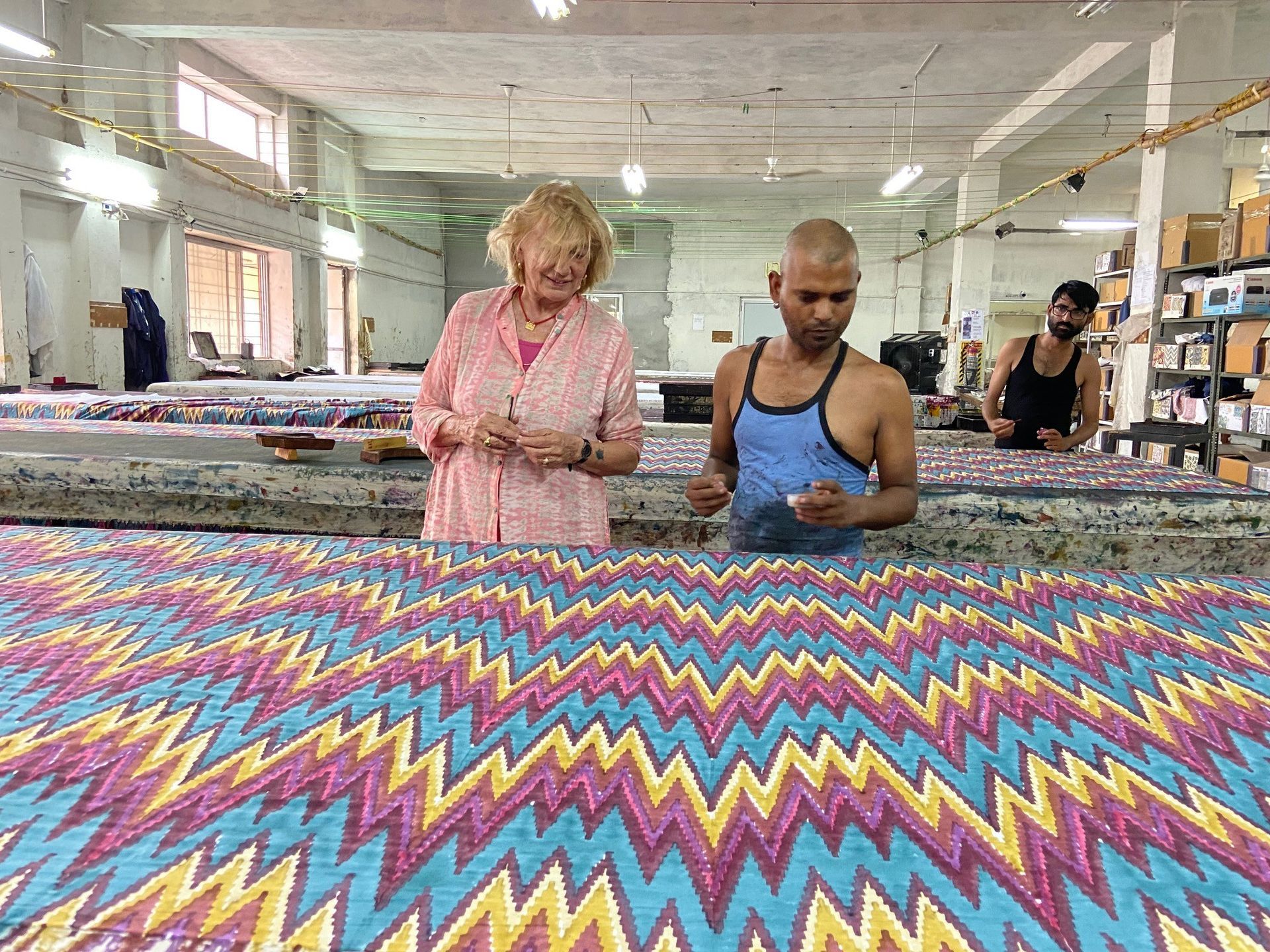 Donna e operaio esaminano un tessuto a zigzag colorato in una fabbrica.