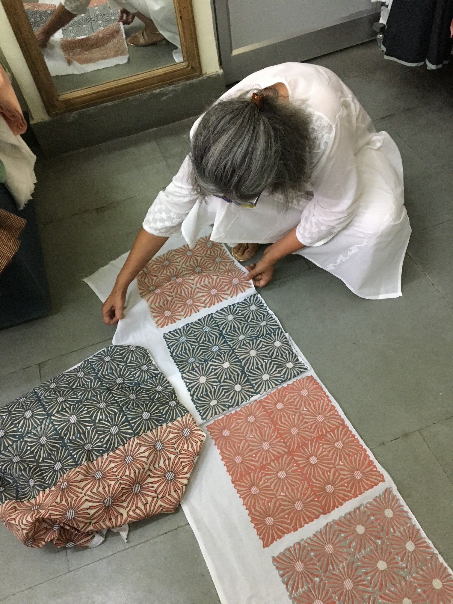 Persona che sistema un tessuto fantasia su una superficie bianca, in un ambiente interno.