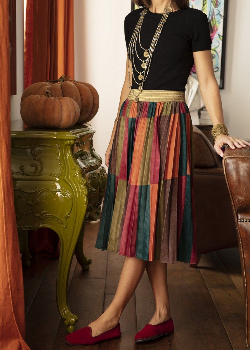 Donna in abito floreale, a piedi nudi sull'erba. Motivo verde, blu e giallo.