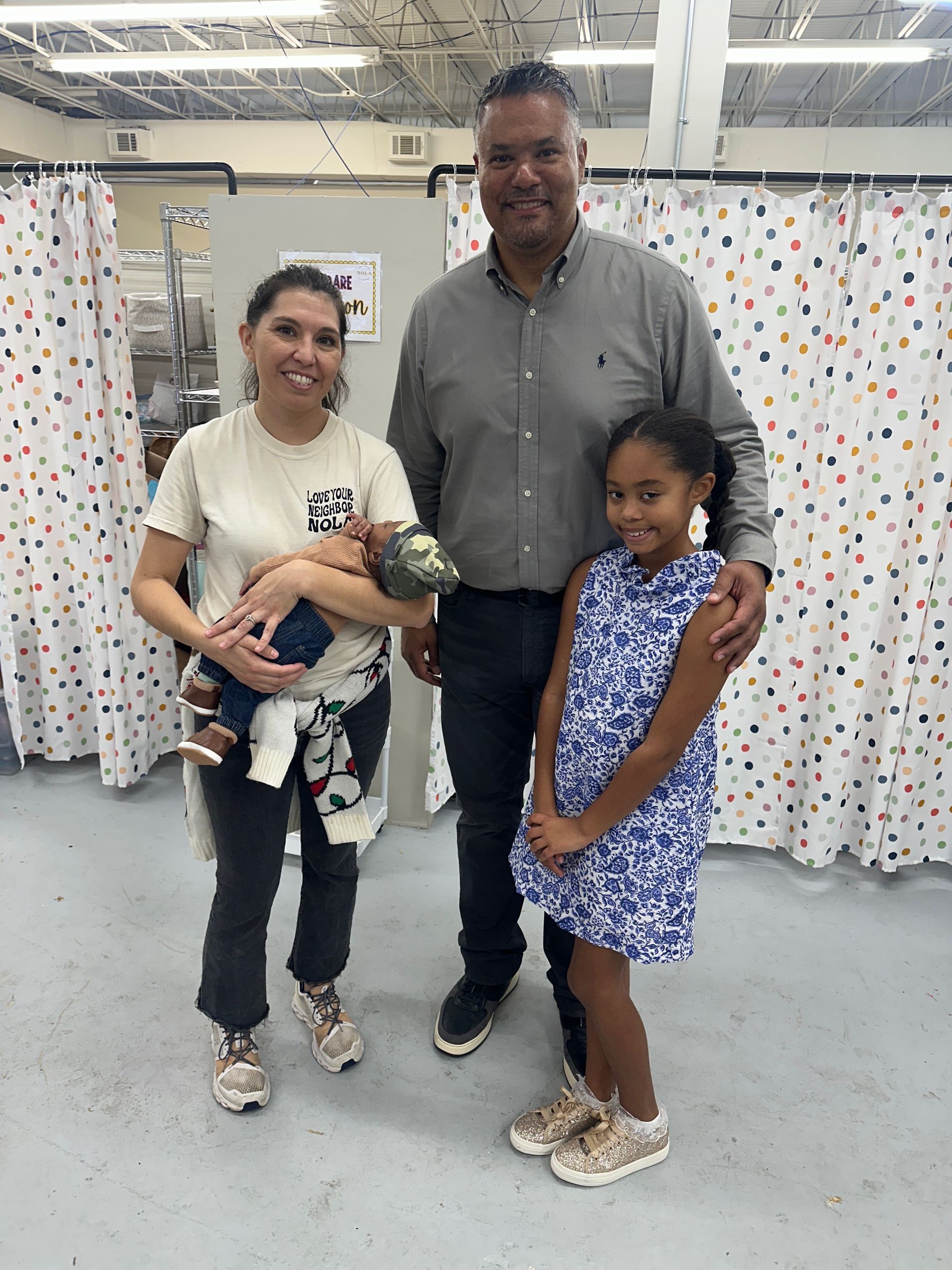 Family of four in a hospital room, including a newborn, smiling.