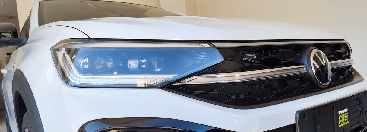 Parte anteriore bianca di auto Volkswagen con griglia e fari neri.