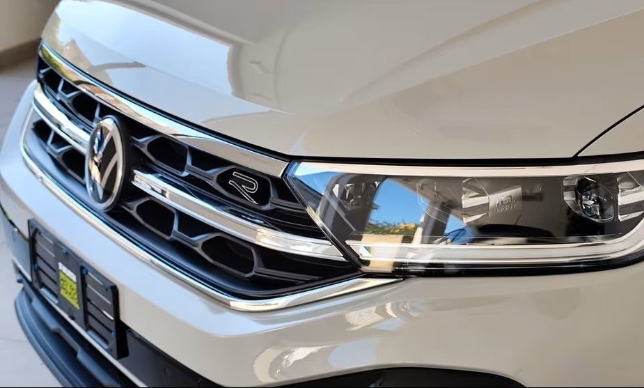 Primo piano della parte anteriore di una Volkswagen bianca, che mostra la griglia, il faro anteriore e il logo.
