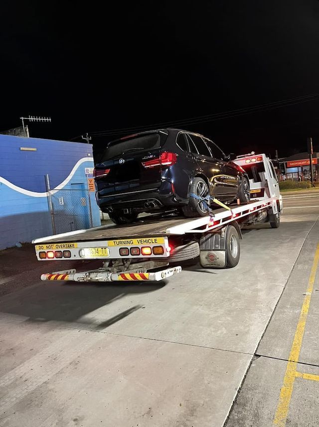A Car is Being Towed by a Tow Truck at Night — TNT Towing - Coffs Clarence in South Grafton, NSW