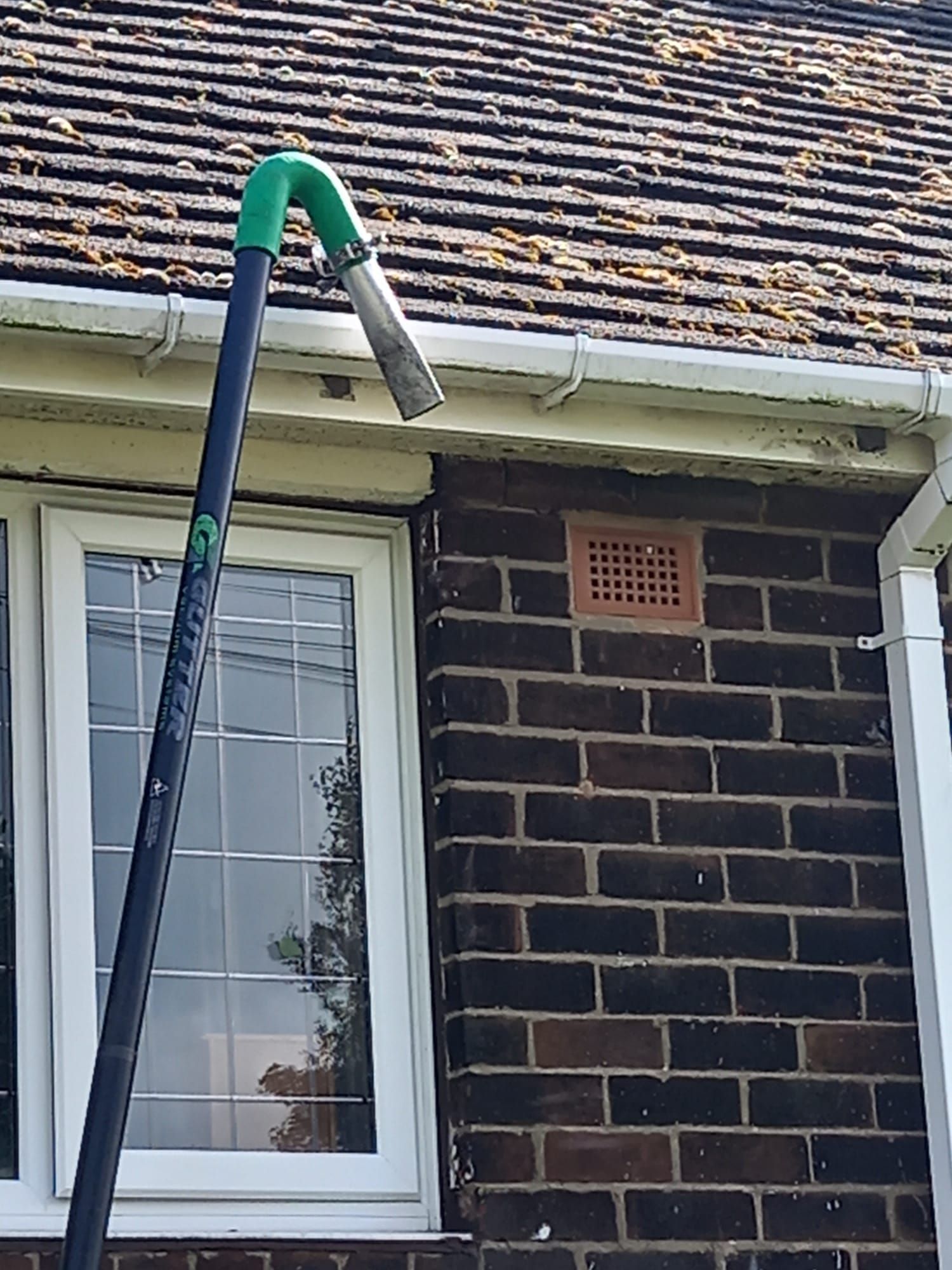 A gutter vacuum is being used to clean the gutters of a brick house.