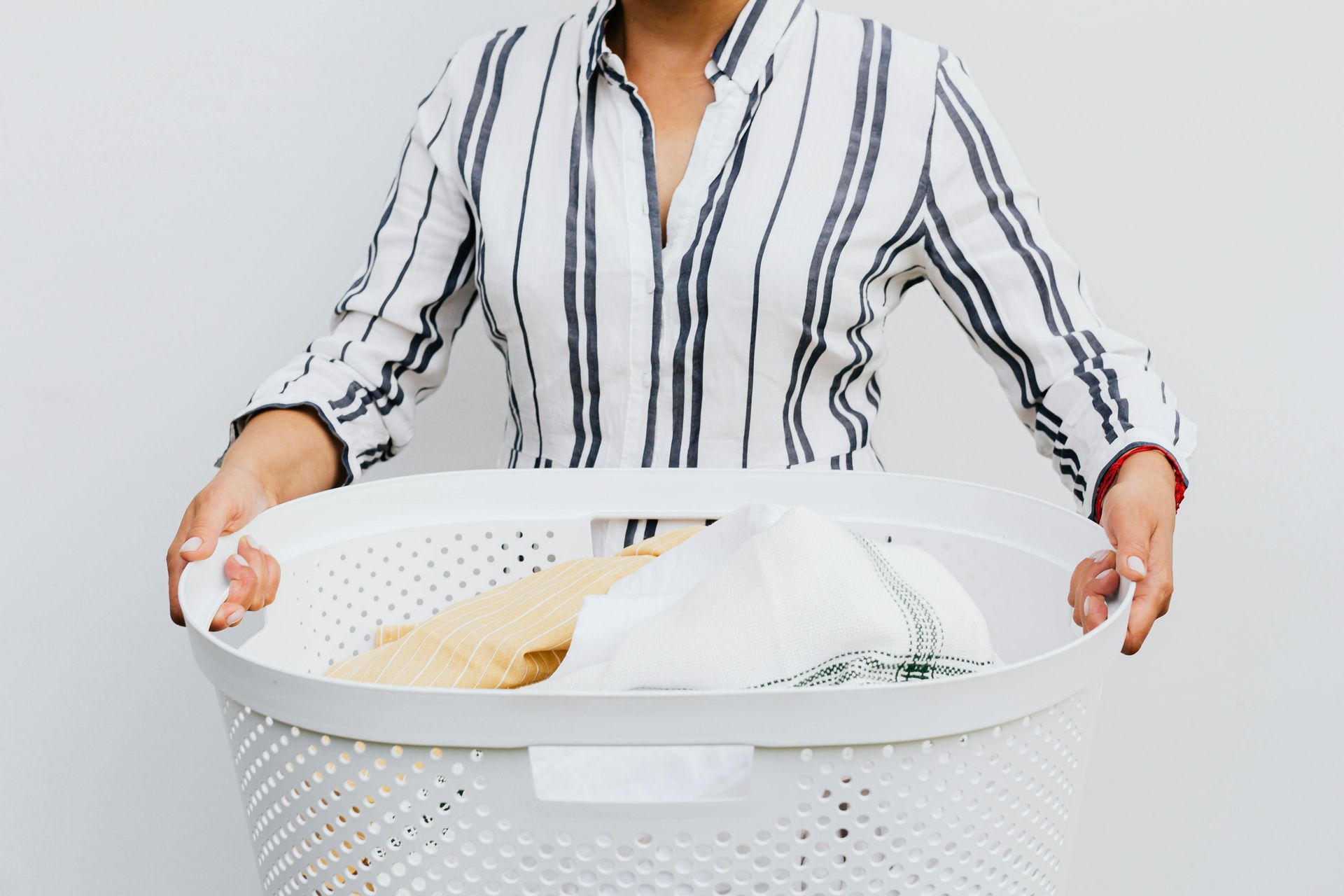 A woman is holding a laundry basket full of clothes.